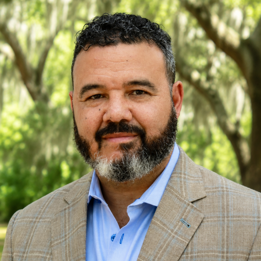Bearded man in a taupe suit with a light blue collared shirt