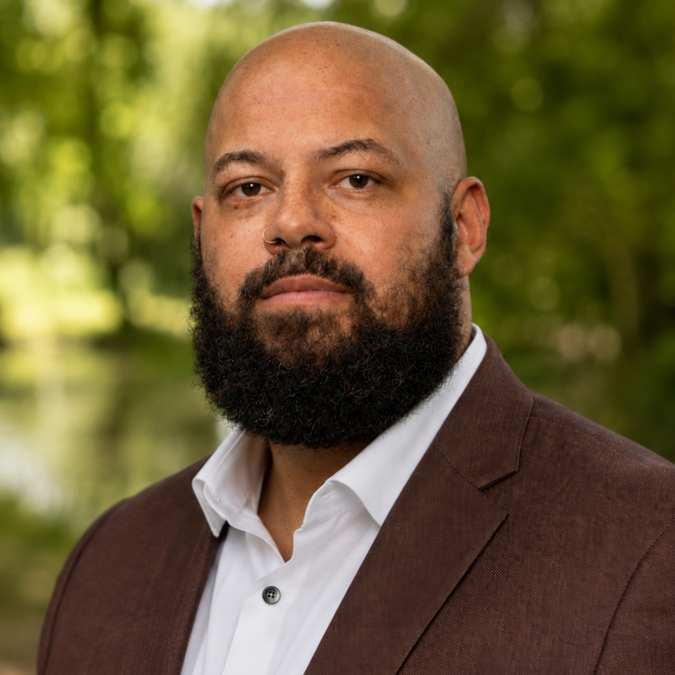 Bearded man wears a brown suit and white collared shirt